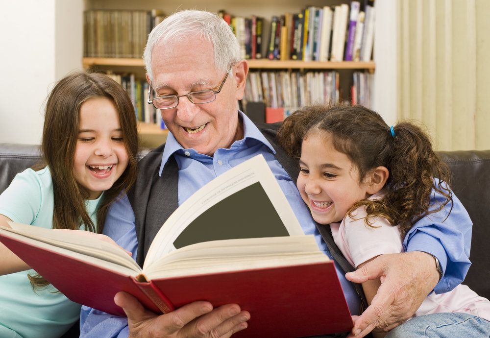 A grandpa reading to his granddaughters