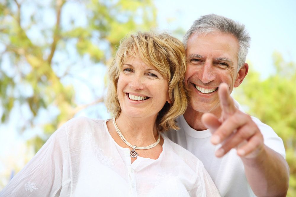 Middle-aged smiling Caucasian couple with husband pointing site out to wife